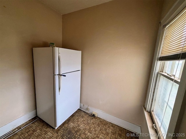 kitchen featuring baseboards, freestanding refrigerator, and a healthy amount of sunlight