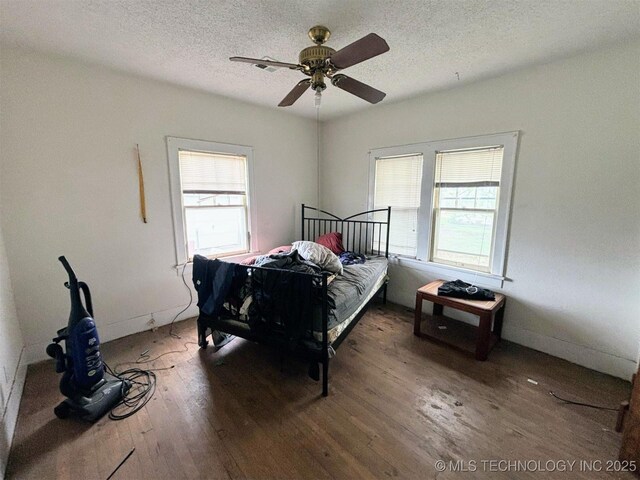 bedroom featuring wood finished floors, a textured ceiling, and multiple windows