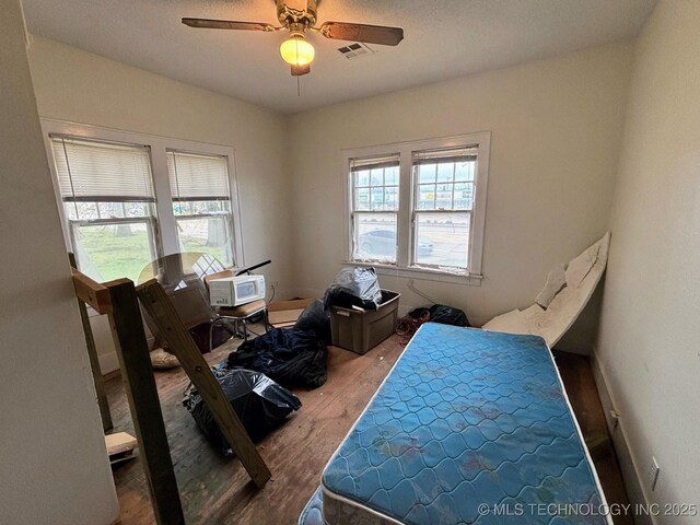 bedroom featuring wood finished floors, visible vents, and a ceiling fan