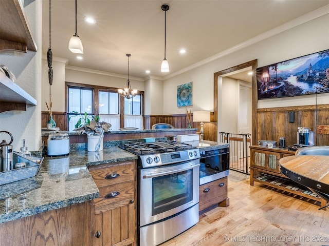 55 Boardwalk, Carlton Landing, OK 74432 - kitchen with stainless steel gas stove, light wood-style flooring, wainscoting, ornamental molding, and brown cabinetry