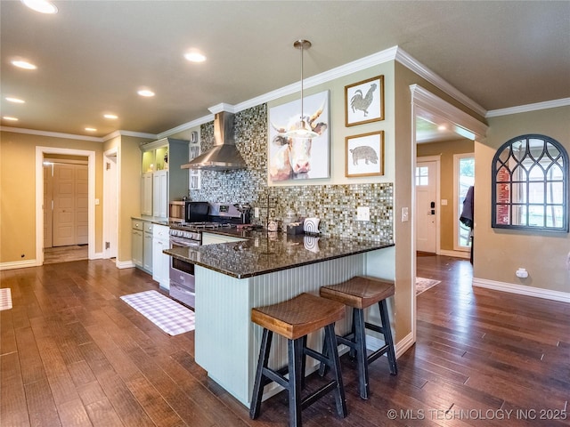 509 Dove Dr, Mcalester, OK 74501 - kitchen featuring wall chimney range hood, backsplash, dark wood-style flooring, gas range, and a breakfast bar