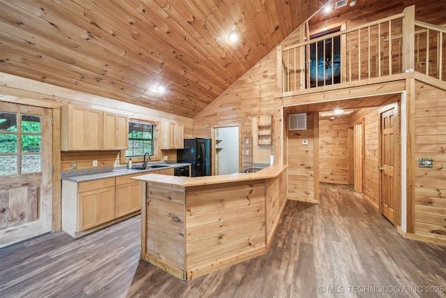 kitchen featuring wood finished floors, high vaulted ceiling, a sink, light brown cabinets, and wooden walls