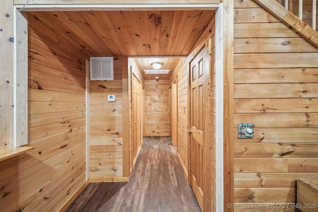 hall with wooden ceiling, wooden walls, visible vents, and wood finished floors