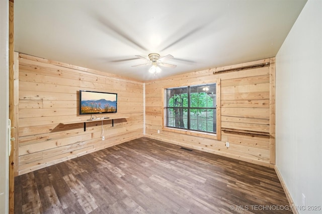 unfurnished room featuring wooden walls, ceiling fan, and dark wood-type flooring