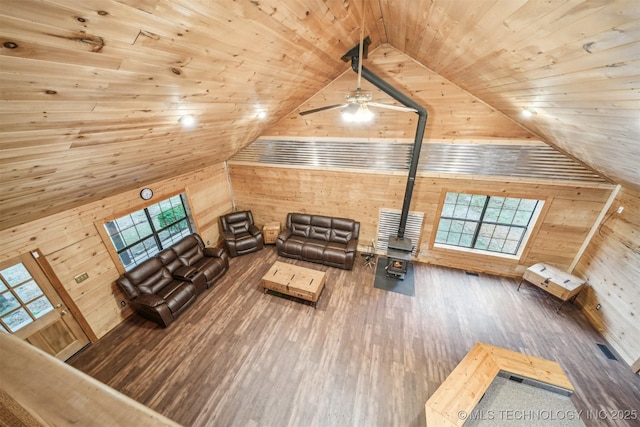 living room featuring a wood stove, wooden ceiling, wood walls, and wood finished floors