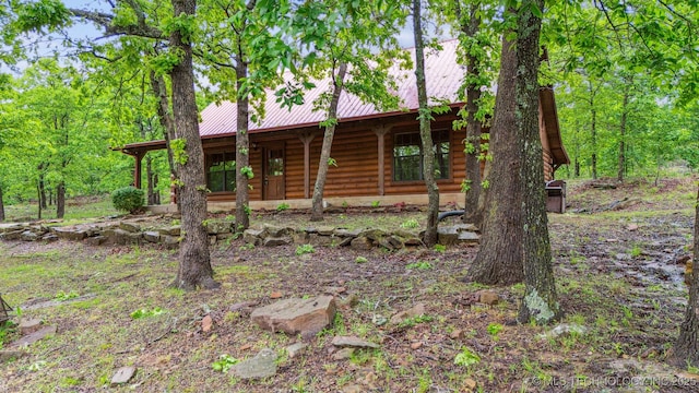 view of front of house with a porch, log siding, and metal roof