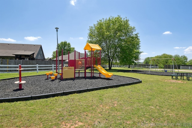 community jungle gym featuring a lawn and fence
