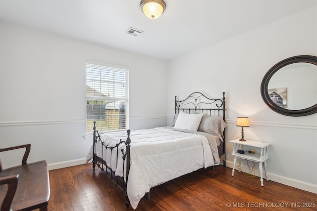 bedroom with visible vents, baseboards, and wood finished floors
