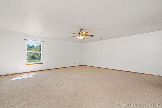 spare room featuring light carpet, a ceiling fan, and baseboards