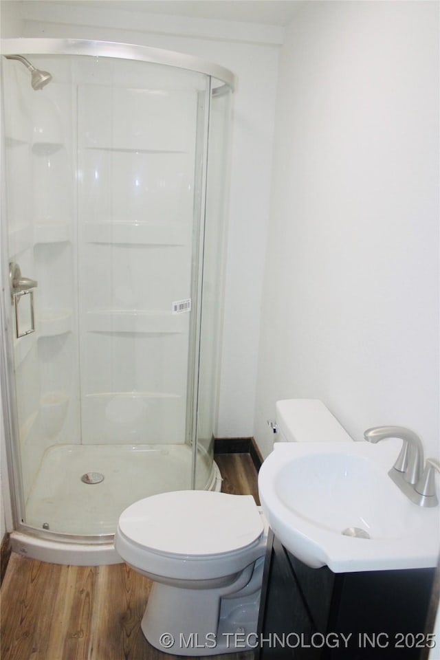 bathroom with baseboards, wood finished floors, a shower stall, and toilet