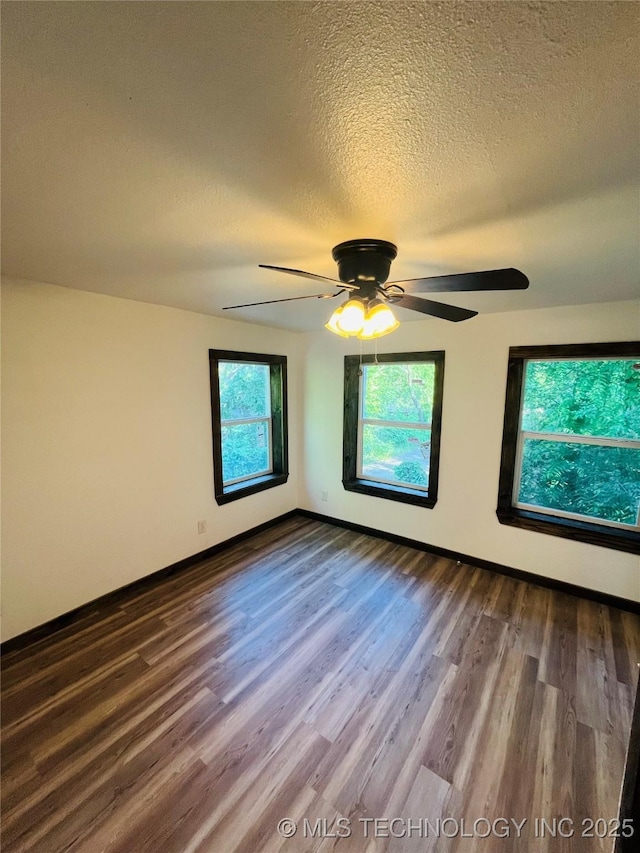 spare room with baseboards, wood finished floors, ceiling fan, and a textured ceiling