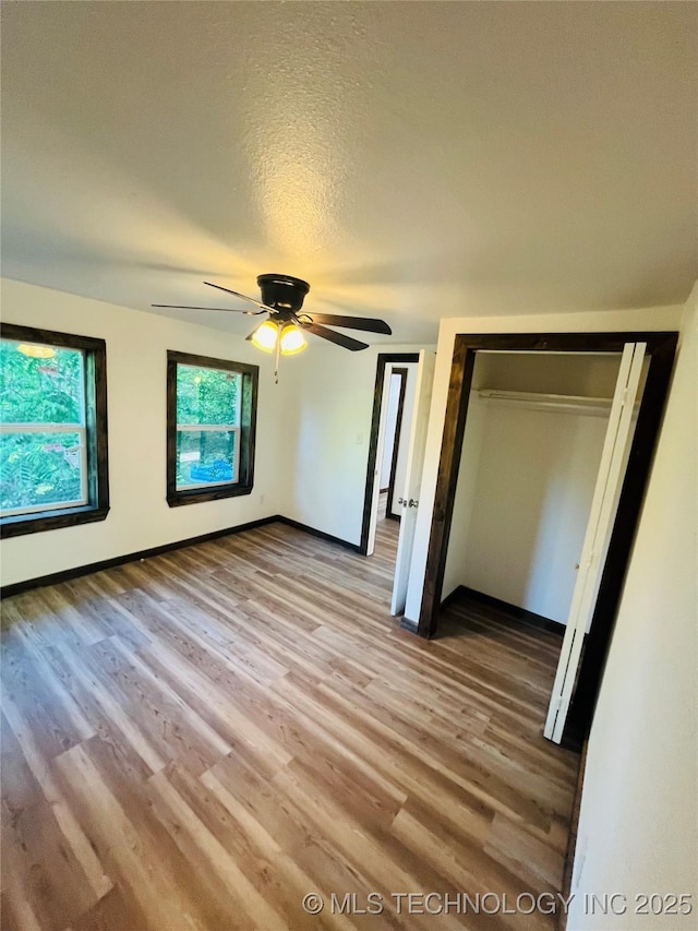 unfurnished bedroom featuring light wood finished floors, a closet, ceiling fan, and baseboards