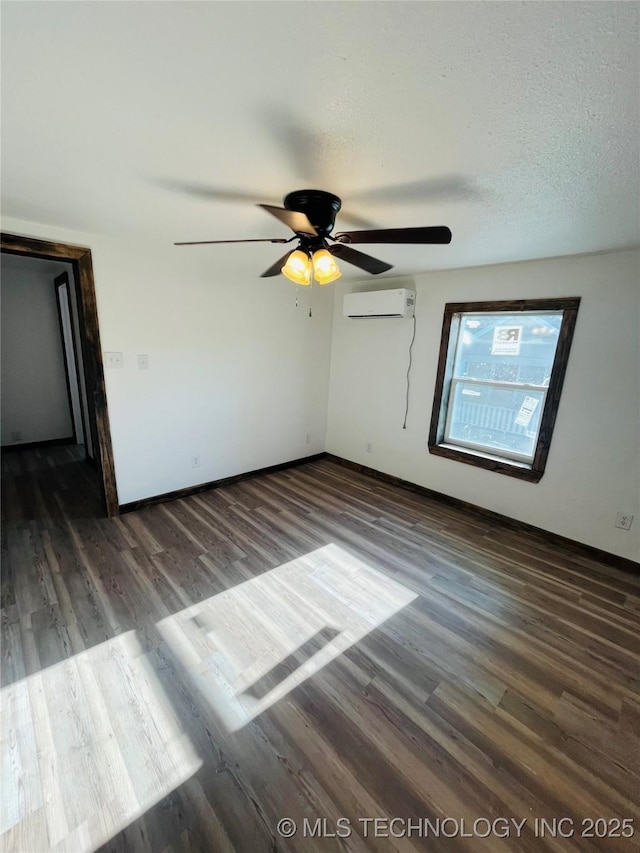 unfurnished bedroom featuring wood finished floors, ceiling fan, a wall mounted air conditioner, and baseboards