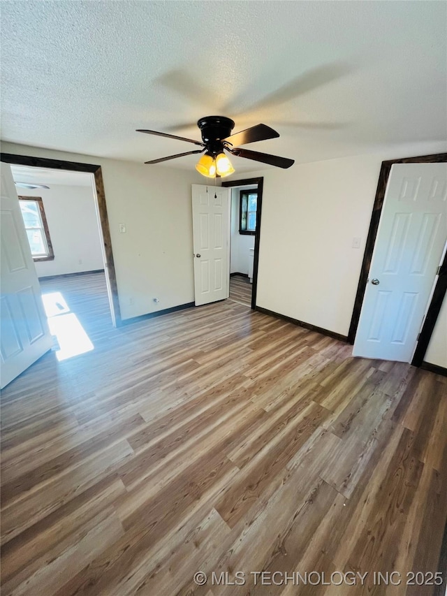 unfurnished bedroom featuring a textured ceiling, wood finished floors, a ceiling fan, and baseboards