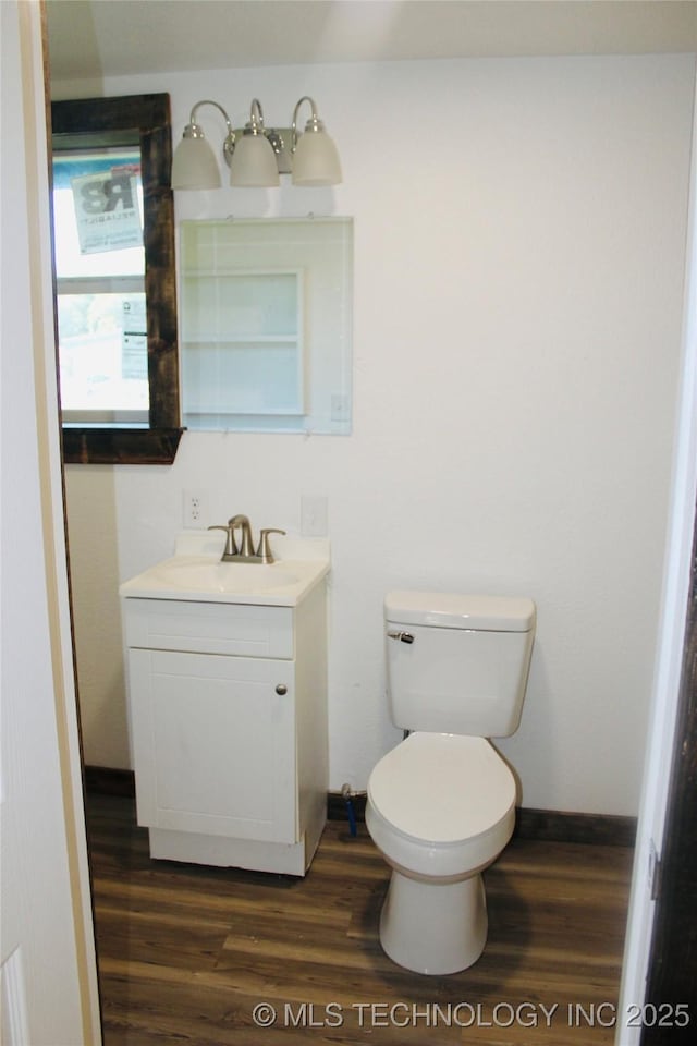 bathroom featuring toilet, vanity, wood finished floors, and baseboards