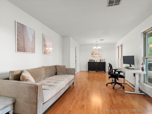 living room with an inviting chandelier, visible vents, and light wood finished floors