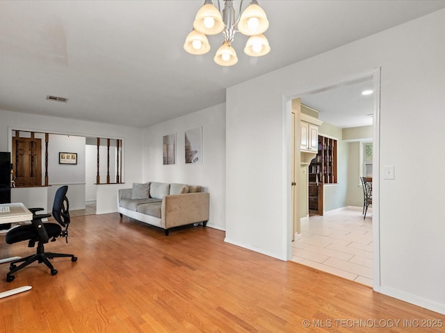 office area featuring light wood finished floors, visible vents, a notable chandelier, and baseboards
