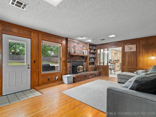 living area featuring wood walls, wood finished floors, visible vents, and a wood stove