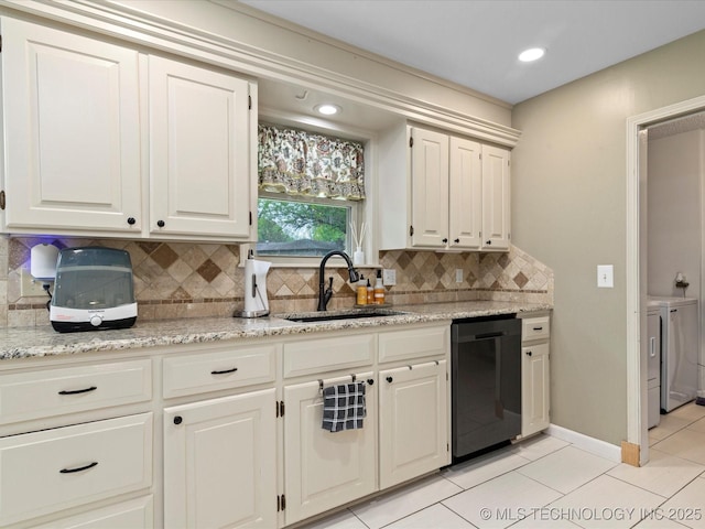 kitchen featuring a sink, decorative backsplash, washer and clothes dryer, black dishwasher, and light tile patterned floors