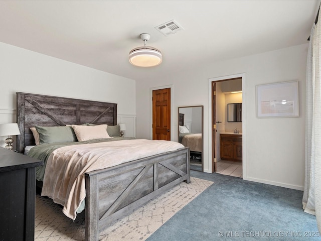 bedroom with a sink, light colored carpet, visible vents, ensuite bathroom, and baseboards