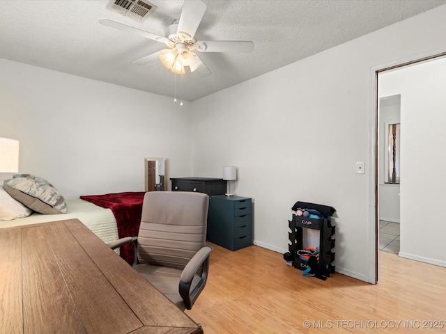 office space featuring a textured ceiling, visible vents, ceiling fan, and light wood-style flooring
