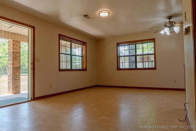 spare room with a healthy amount of sunlight, ceiling fan, visible vents, and baseboards