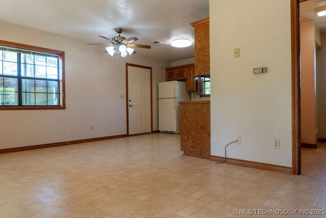 unfurnished room featuring ceiling fan, visible vents, and baseboards