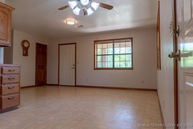 unfurnished room with baseboards, visible vents, a ceiling fan, and a textured ceiling