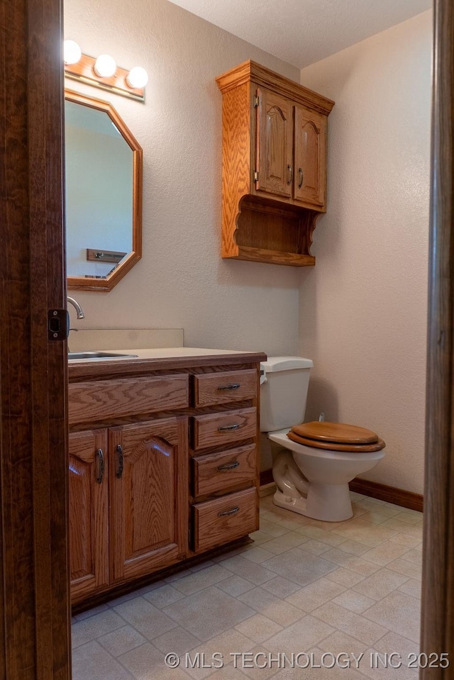 bathroom with toilet, vanity, and baseboards