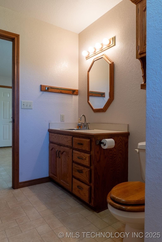 bathroom featuring vanity, toilet, and baseboards