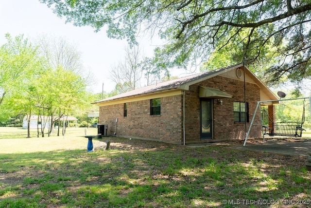 view of side of property featuring brick siding and central AC unit
