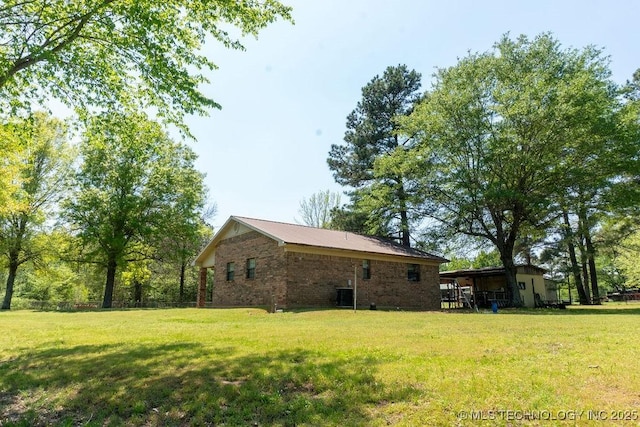 view of side of property featuring a lawn, central AC, and brick siding