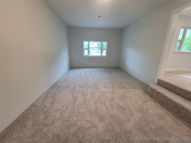 carpeted empty room with visible vents and stairway