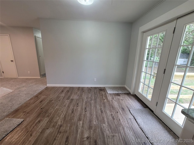 unfurnished room with baseboards, wood finished floors, a healthy amount of sunlight, and ornamental molding