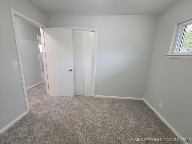 unfurnished bedroom with crown molding, carpet flooring, and a closet