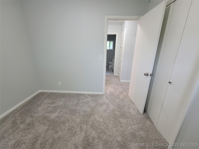 empty room featuring baseboards and light carpet