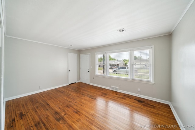spare room featuring hardwood / wood-style floors, visible vents, crown molding, and baseboards