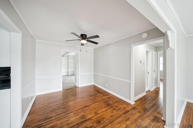 spare room featuring baseboards, ornamental molding, a ceiling fan, and dark wood-style flooring