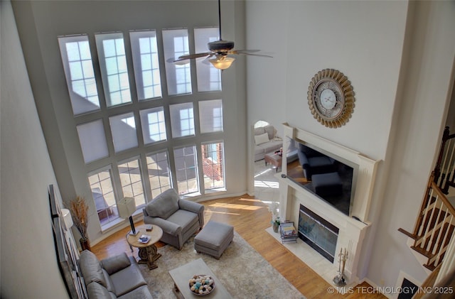 8160 S 270th E Ave, Broken Arrow, OK 74014 - living area with a fireplace with flush hearth, ceiling fan, a towering ceiling, and light wood-style flooring