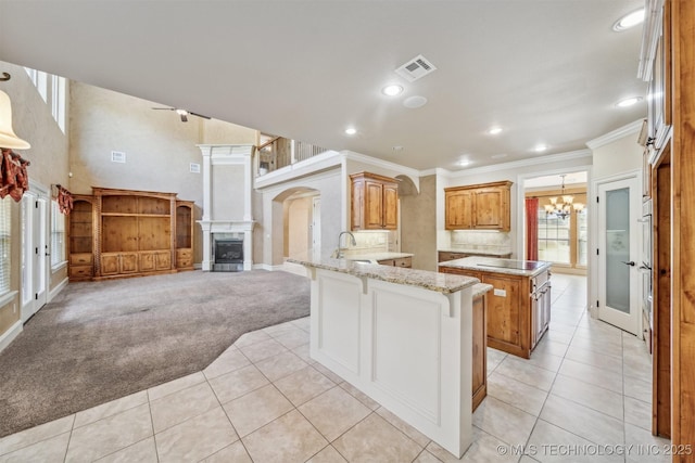 19434 S Quail Run Ct, Claremore, OK 74017 - kitchen with light tile patterned floors, a peninsula, a chandelier, a sink, and ornamental molding