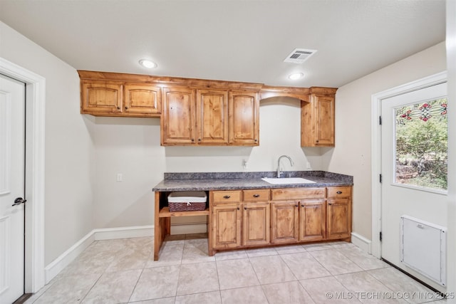 19434 S Quail Run Ct, Claremore, OK 74017 - kitchen featuring dark countertops, a sink, brown cabinetry, light tile patterned floors, and baseboards