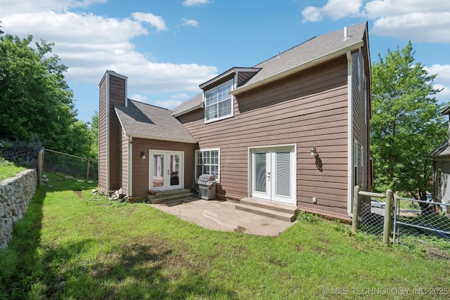 rear view of property with a fenced backyard, french doors, a chimney, entry steps, and a yard