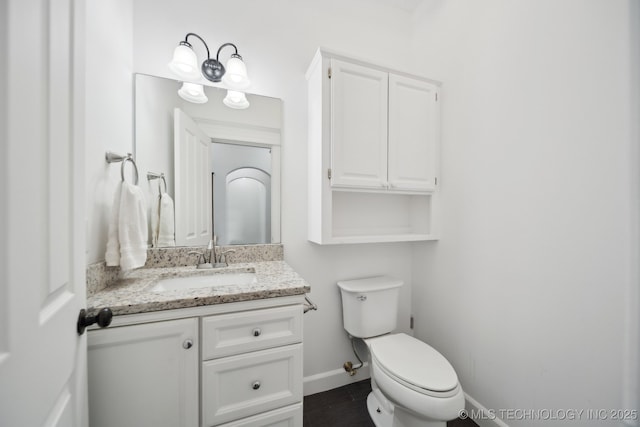 bathroom with baseboards, toilet, and vanity