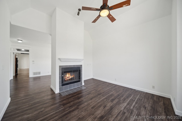unfurnished living room with visible vents, dark wood-style floors, vaulted ceiling, and a tile fireplace