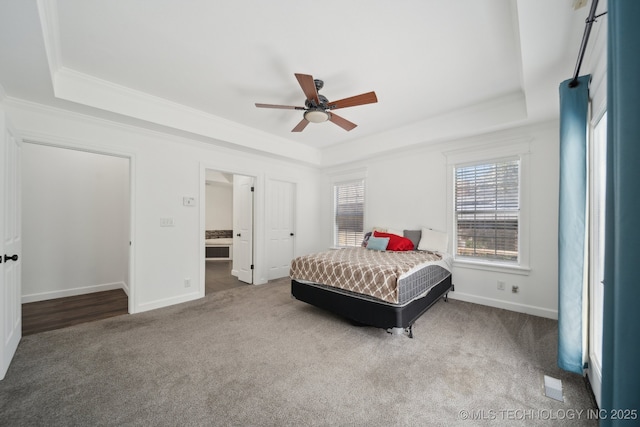 carpeted bedroom with crown molding, baseboards, ceiling fan, and a tray ceiling