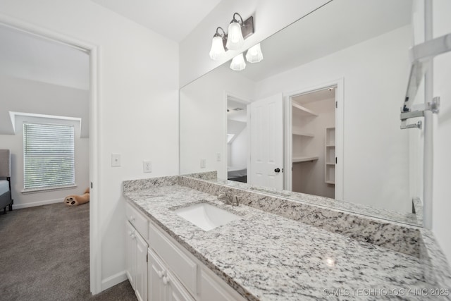 ensuite bathroom with connected bathroom, baseboards, and vanity