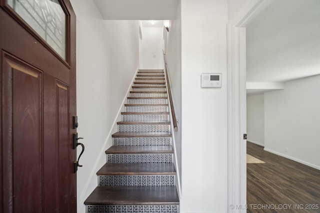 staircase featuring baseboards and wood finished floors