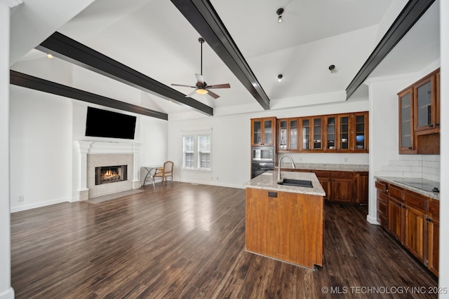 kitchen with brown cabinetry, a kitchen island with sink, ceiling fan, a sink, and black appliances