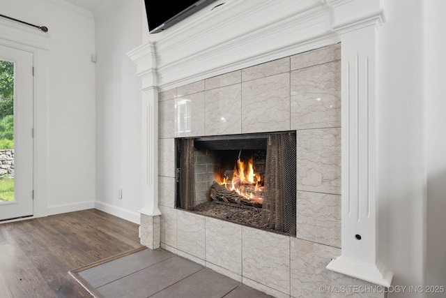 details with baseboards, ornamental molding, a fireplace, and wood finished floors