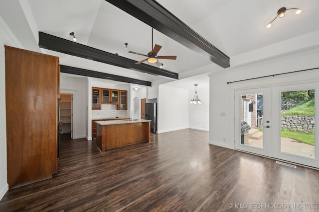 unfurnished living room featuring dark wood-style flooring, a sink, french doors, ceiling fan with notable chandelier, and beamed ceiling